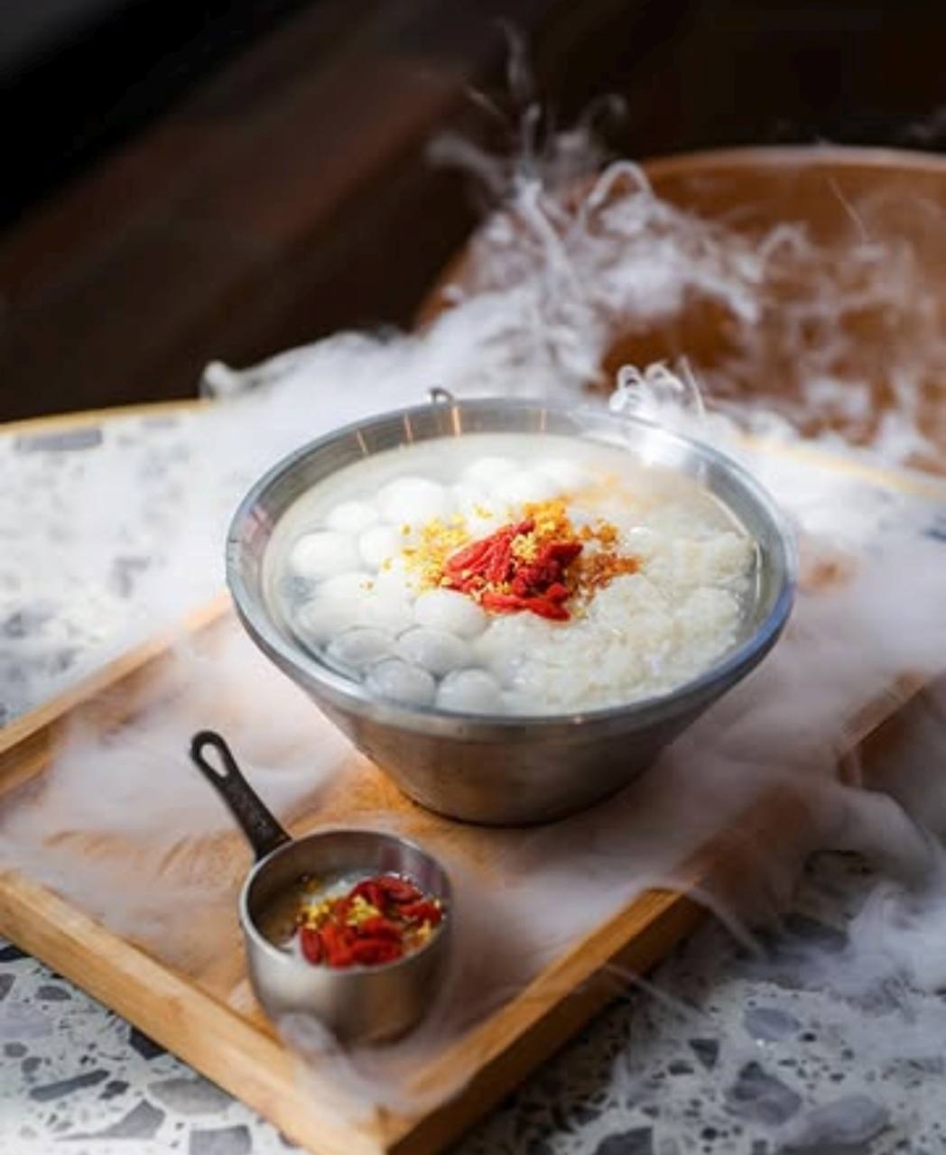 A LÜCHA dessert bowl with red berry garnish and mist on a wooden tray