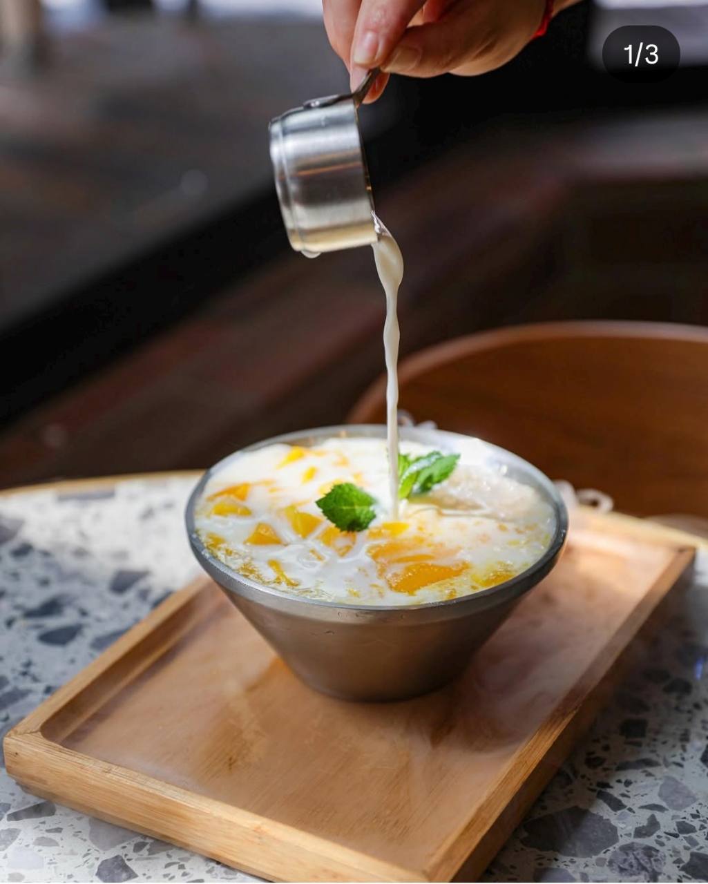 A creamy mango dessert served on a wooden tray at LÜCHA