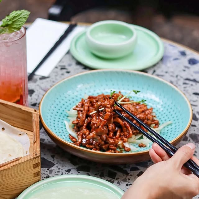 A shared Chinese dish beside a tea cup at LÜCHA in Brisbane CBD